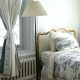 Décor d'une chambre décorée d'un rideau noué et de draps de lit en toile de Louy blanche et bleue
